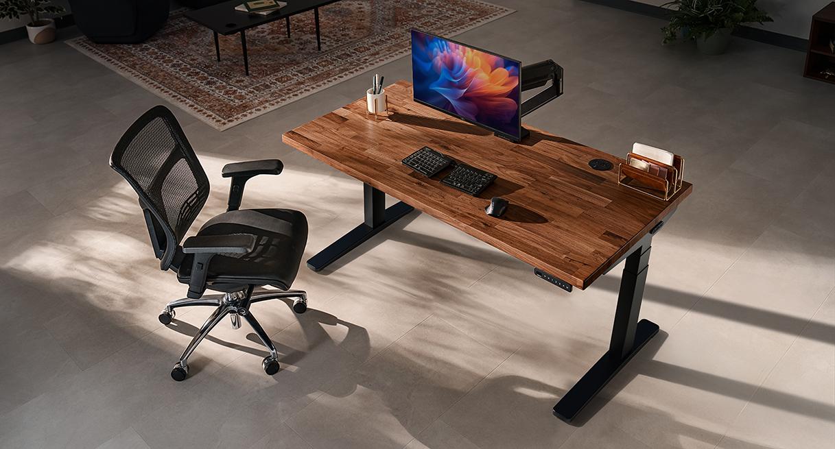 UPLIFT V3 walnut standing desk and black frame in a sunlit workspace with a mesh chair