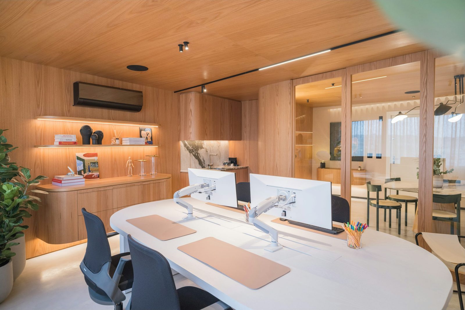 Workspace context: a shared work area with separate screen arms and seating. Furniture and mounting hardware models are not established here.